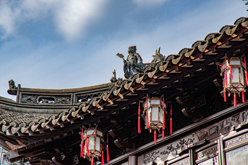 Chinese temple of heaven. Ornate edge of ancient tiled roof of pagoda with vintage lanterns and sculptural details on blue sky background. Architecture of antique building in YuYuan Garden of Shanghai
