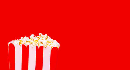 Fototapeta na wymiar Large square striped box with salty popcorn on red background. Cinema concept,with clipping path