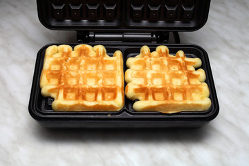 homemade waffles on an electric waffle iron on a light table