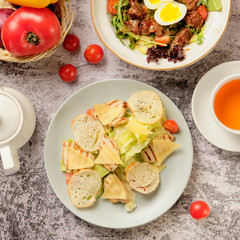 Restaurant cold caesar salad with chicken, cherry tomato, green leaves and herbs on a stone background. Food and drink concept.