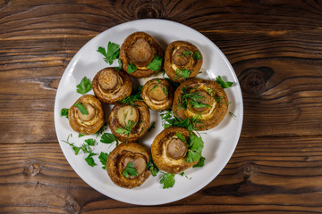 Baked mushrooms in plate on wooden table. Top view