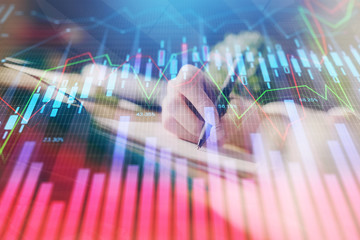 Financial forex graph displayed on hands taking notes background. Concept of research. Multi exposure