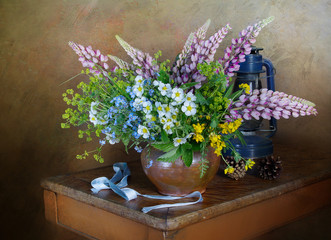 Still life with a bouquet of wild flowers in a clay vase on the table