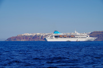 White classic cruiseship or cruise ship liner anchored in bay of volcanic Greek Island of Santorini...