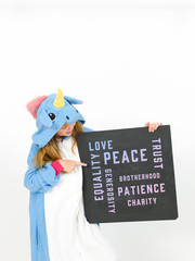 pretty blonde girl with cozy blue unicorn costume with blackboard with different words on it like love and peace and some more