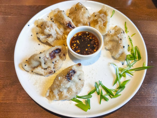 Asian fried dumplings with soy sauce on a plate and greens.