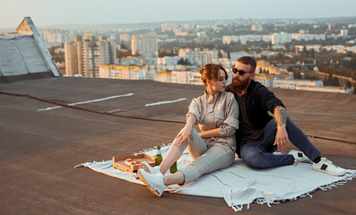 Trendy couple having picnic on roof