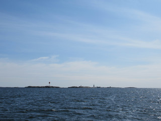 Seascape with small islands and a lighthouse on a sunny day.