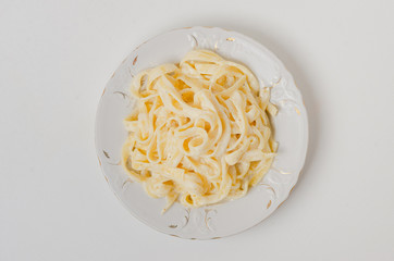 Traditional Italian pasta - Fetuccini Alfredo on a white table with golden appliances