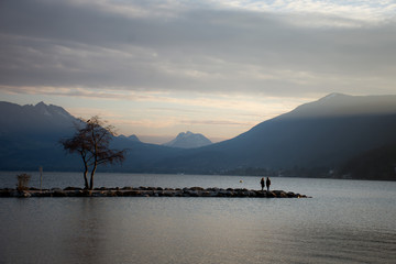 sunset on lake with silhouettes of people and tree