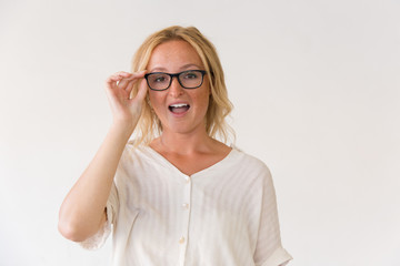Surprised blonde woman in spectacles. Portrait of emotional young woman adjusting eyeglasses and looking at camera. Surprise concept