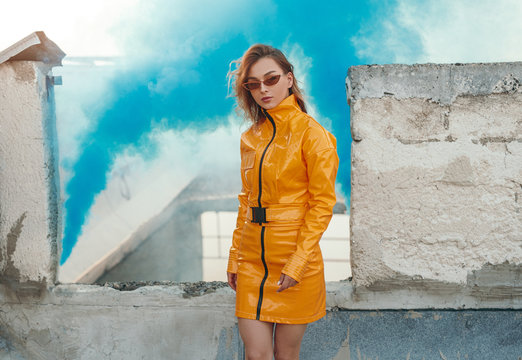 Trendy woman near smoke grenade on grungy rooftop