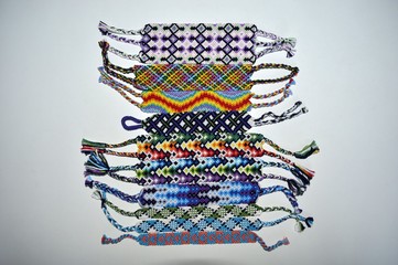 Multicolored friendship bracelets with different patterns handmade of embroidery floss and thread isolated on white background