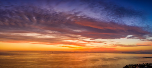 Luftaufnahme eines romantischen Sonnenunterganges über dem Meer mit roten und violetten Farbtönen
