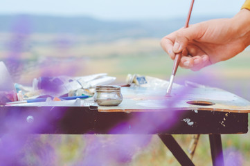 Close up view on the hands and tools of an artist. Colorful workplace of the artist with oilcan and...