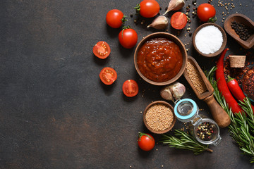 Tomato sauce with spices and chili peppers on a stone table.
