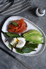 Classic breakfast - poached egg, bread and salmon on a stone table.