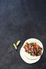 Classic Mexican dish - corn tortilla with vegetables and beef on a kitchen stone table. Top view with copy space on text.
