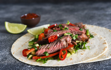 Classic Mexican dish - corn tortilla with vegetables and beef on a kitchen stone table.