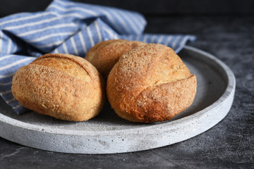 Whole grain bread in a plate on concrete against dark background.