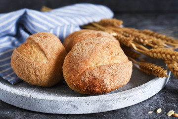 Whole grain bread in a plate on concrete against dark background.