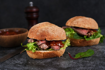Bun with beef, salad and sauce. Hamburger.