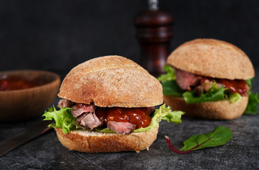 Bun with beef, salad and sauce. Hamburger.