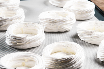 Round-shaped meringues on baking sheet. Close-up of baked crispy dessert. Recipe concept