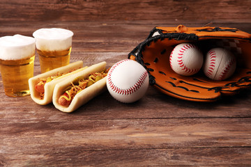 Grilled hot dogs with mustard and ketchup on the table with draft beer. Baseball party food with balls for the playoffs