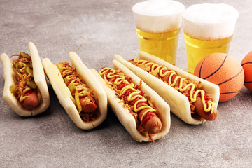 Grilled hot dogs with mustard and ketchup on the table with draft beer. Television watching basketball game with eating snacks and drinking beer
