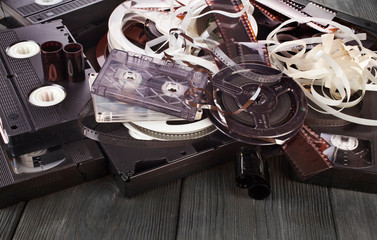 Vintage film camera rolls, old audio and video casettes with tape and foto strip on a wooden...