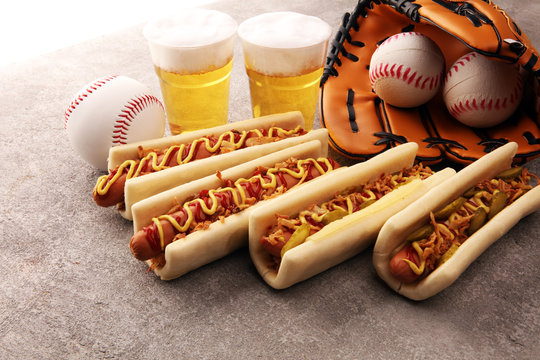 Grilled hot dogs with mustard and ketchup on the table with draft beer. Baseball party food with balls for the playoffs