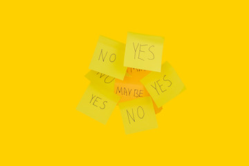 several yellow sticker with black ink that says yes, no, may be on an orange background