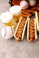 Grilled hot dogs with mustard and ketchup on the table with draft beer. Baseball party food with balls for the playoffs