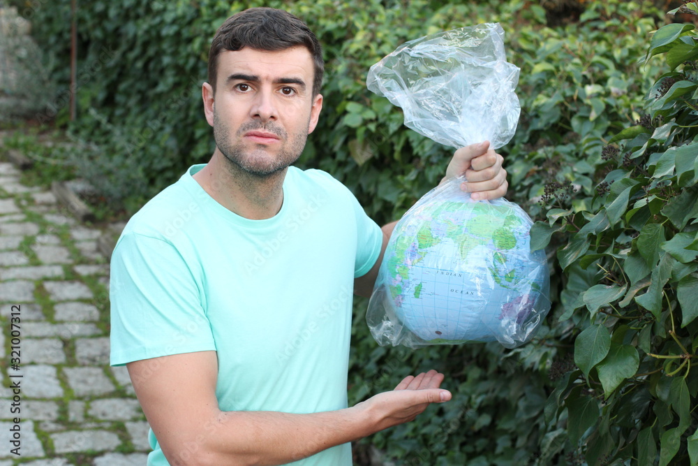 Wall mural sad man carrying the planet in a plastic bag