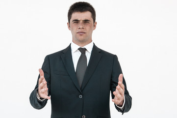 Serious sales agent advertising product or service. Young man in jacket and tie holding air or copy space by hands. Male business portrait concept
