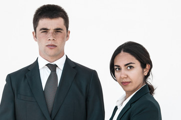 Serious successful business colleagues posing against white background. Portrait of young man and woman in formal suits. Business team concept