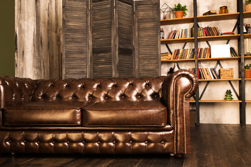 Brown leather sofa in an interior room with a bookcase.
