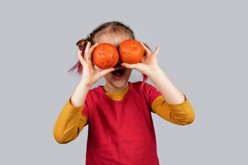 Freakish kid holds misshapen wrong color fruits and vegetables, waste food concept