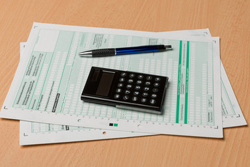 forms for a tax declaration, a pen and a calculator
