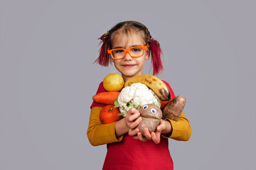 Freakish kid holds misshapen wrong color fruits and vegetables, waste food concept