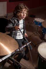 Curly-haired boy and gray shirt of shirtmakers playing drums like a pro. Fun and passion playing music