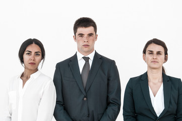 Fototapeta na wymiar Corporate portrait of serious successful business team. Three young business people standing for camera against white background. Business team concept