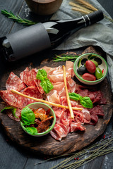 Italian meat appetizers and wine on a wooden tray. Wine mock-up and Antipasto, salami, prosciutto, slices ham, beef jerky and bread sticks.