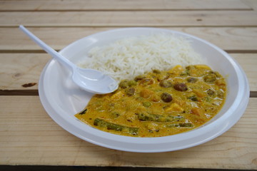 Indian curry and rice portion on a plastic plate with a plastic fork