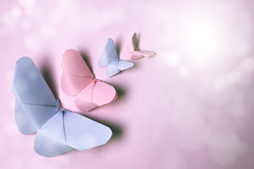 Pink and violet origami butterflies of different sizes on isolated pink background with sparkles and vintage air.Card or postcard to dedicate to mother, woman, working woman, birthday, spring.