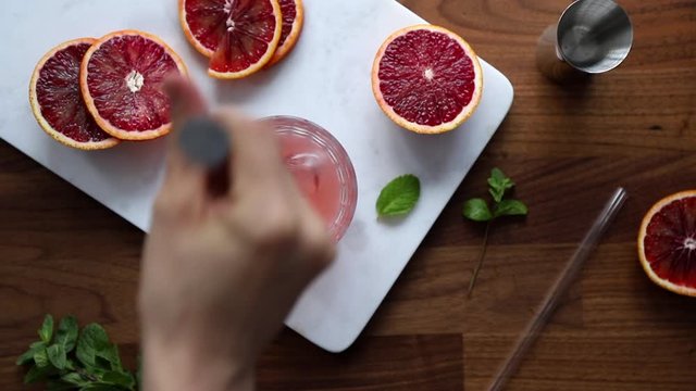Mixing a cold summer cocktail with blood orange and mint.