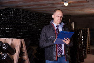 Winemaker with clipboard in wine cellar