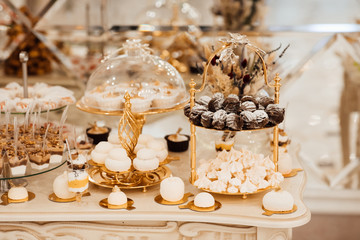 Table full with cakes and sweets at a wedding reception. Wedding candy bar and different cap cakes. Candy bar, a table with sweets and desserts on the table. Buffet with delicious cupcakes, flowers.