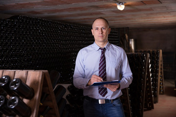 Winemaker with clipboard in wine cellar